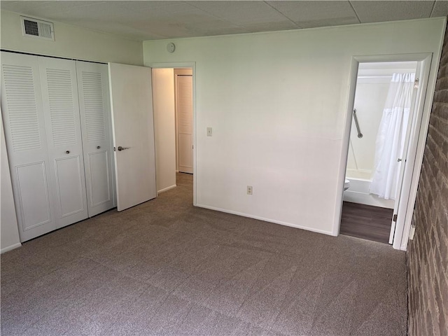 unfurnished bedroom with carpet floors, a closet, connected bathroom, and baseboards