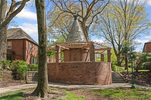 view of side of property featuring a pergola, stairs, and brick siding