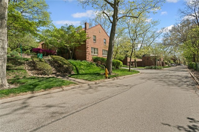 view of asphalt road featuring stairs and curbs