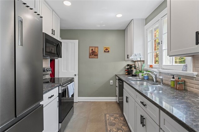 kitchen with black appliances, baseboards, a sink, backsplash, and white cabinetry