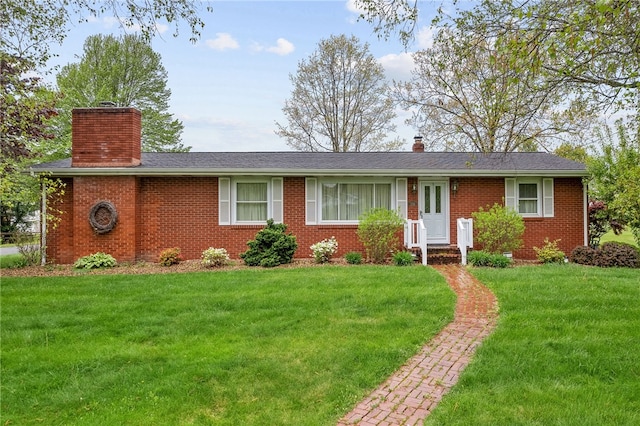ranch-style home featuring a chimney, brick siding, and a front lawn
