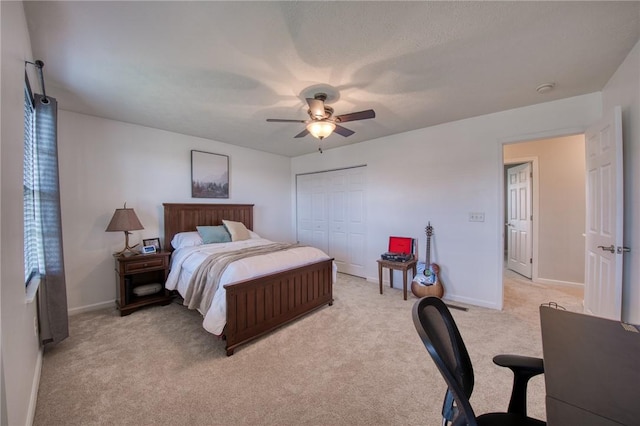 bedroom featuring light colored carpet, a closet, baseboards, and ceiling fan