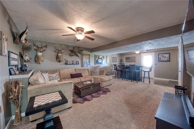 living area with a textured ceiling, a dry bar, ceiling fan, carpet floors, and baseboards