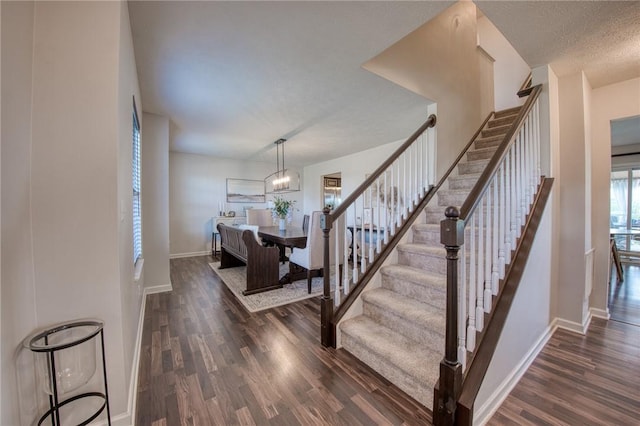 stairs featuring wood finished floors, baseboards, and a chandelier