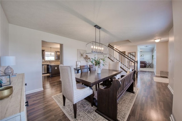 dining area with dark wood-style floors, stairs, baseboards, and a chandelier
