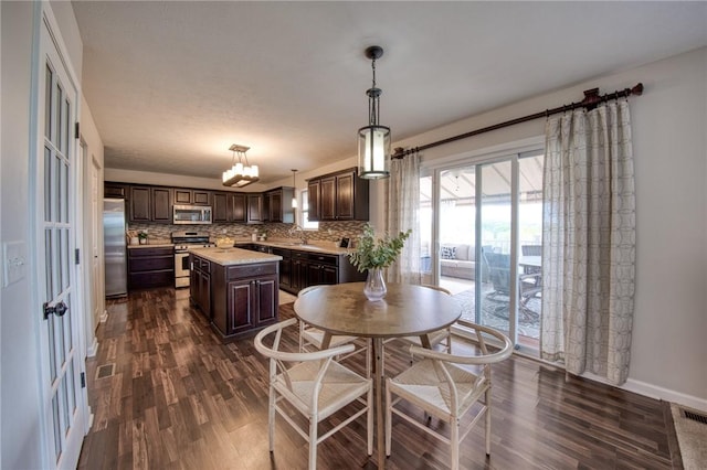 kitchen featuring appliances with stainless steel finishes, dark brown cabinetry, light countertops, and dark wood finished floors