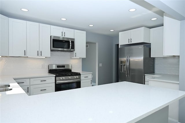 kitchen with stainless steel appliances, recessed lighting, light countertops, backsplash, and white cabinetry