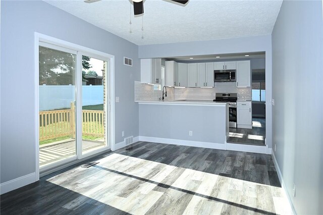 kitchen featuring appliances with stainless steel finishes, dark wood-type flooring, tasteful backsplash, light countertops, and a textured ceiling
