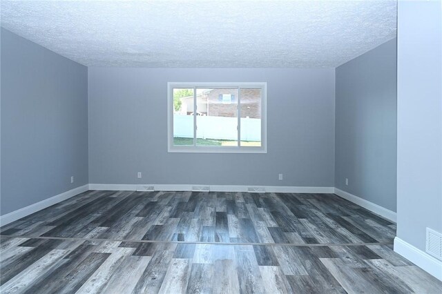 spare room featuring a textured ceiling, wood finished floors, and baseboards