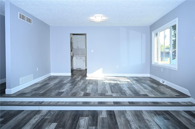 unfurnished room with baseboards, wood finished floors, and a textured ceiling