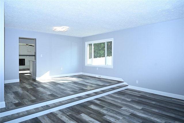 empty room with dark wood-type flooring, baseboards, and a textured ceiling