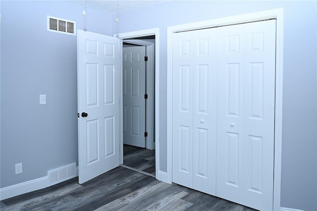 unfurnished bedroom featuring baseboards, a closet, and dark wood finished floors
