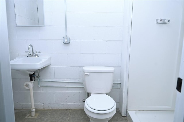 bathroom with toilet and concrete block wall
