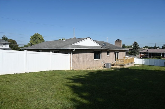 back of house featuring central air condition unit, a deck, a chimney, and brick siding
