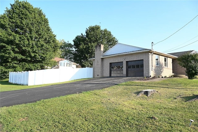 view of side of home featuring driveway, a garage, brick siding, and a chimney