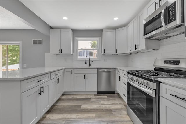 1301 Bechtel St, Monaca, PA 15061 - kitchen featuring appliances with stainless steel finishes, a peninsula, light wood-style floors, backsplash, and recessed lighting
