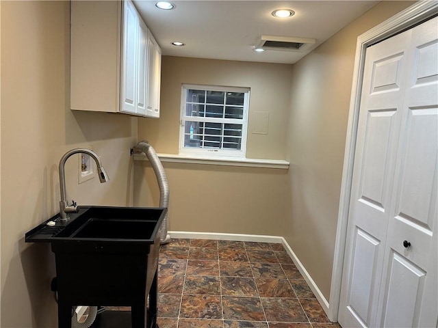 clothes washing area featuring cabinet space, baseboards, dark stone finish floors, washer hookup, and recessed lighting