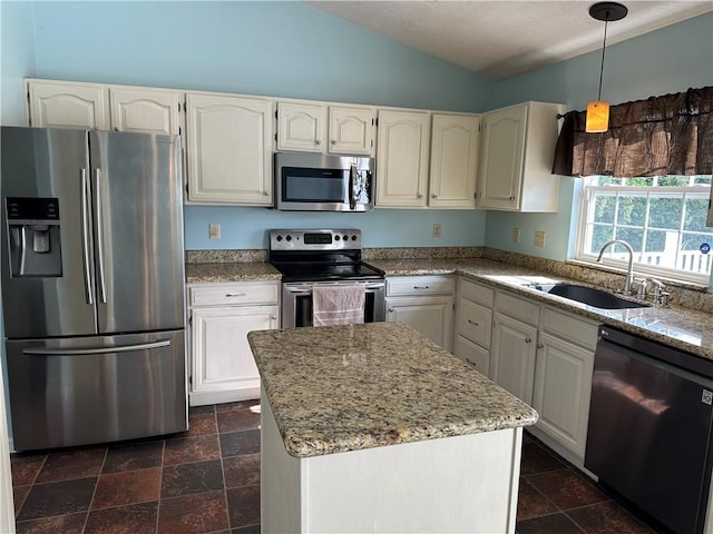 kitchen with appliances with stainless steel finishes, a sink, vaulted ceiling, and light stone counters