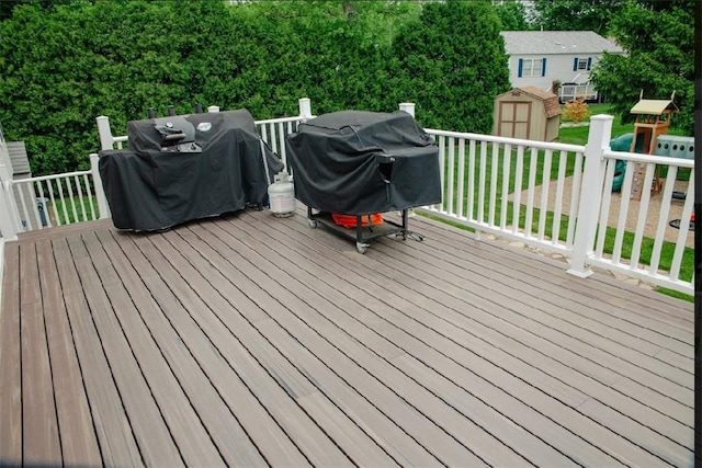 wooden terrace featuring a storage unit, an outbuilding, and a grill