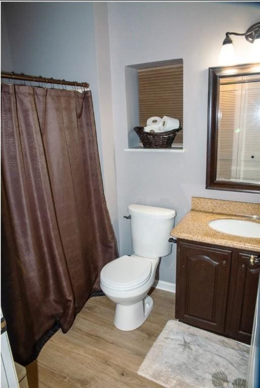 full bath with wood finished floors, vanity, toilet, and baseboards