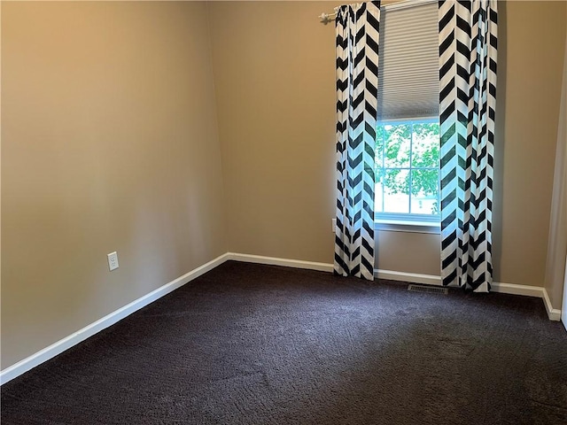 spare room with dark carpet and baseboards