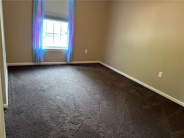 unfurnished room with dark colored carpet and baseboards