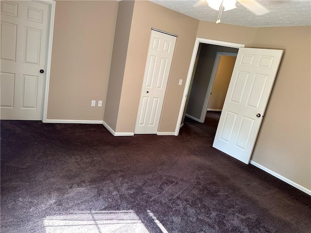 unfurnished bedroom with dark carpet, baseboards, a closet, and a ceiling fan