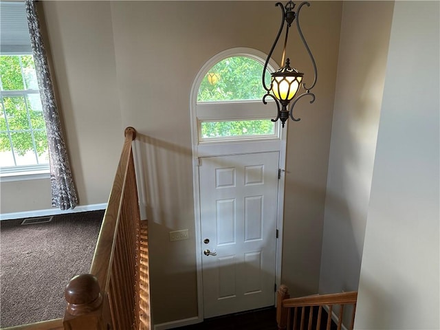 entryway with plenty of natural light, baseboards, and dark carpet