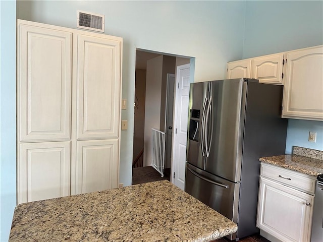 kitchen with stainless steel fridge with ice dispenser and light stone countertops