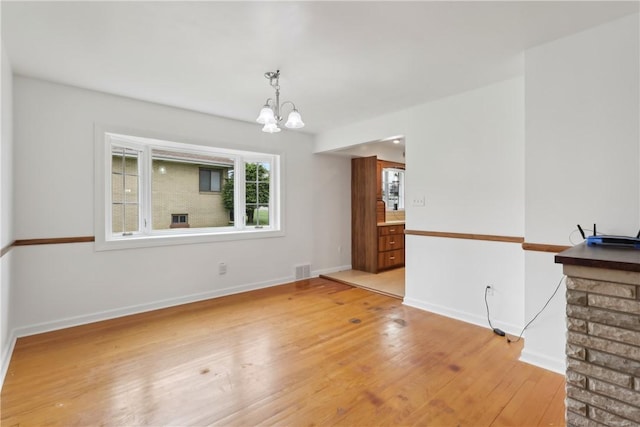 unfurnished dining area with a chandelier, light wood-style flooring, and baseboards