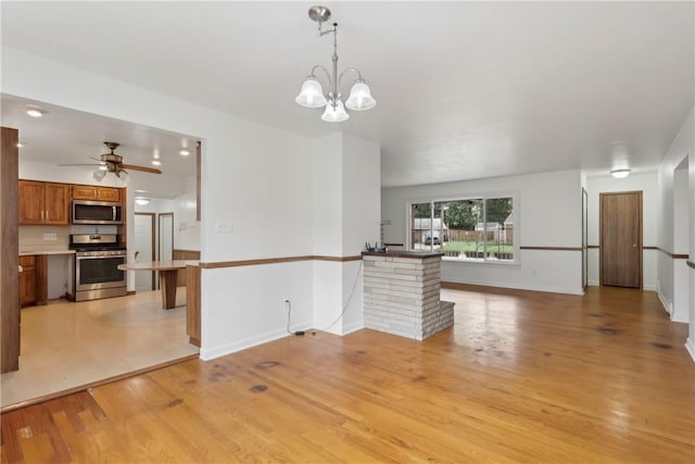 unfurnished living room featuring light wood finished floors, a ceiling fan, a chandelier, and baseboards