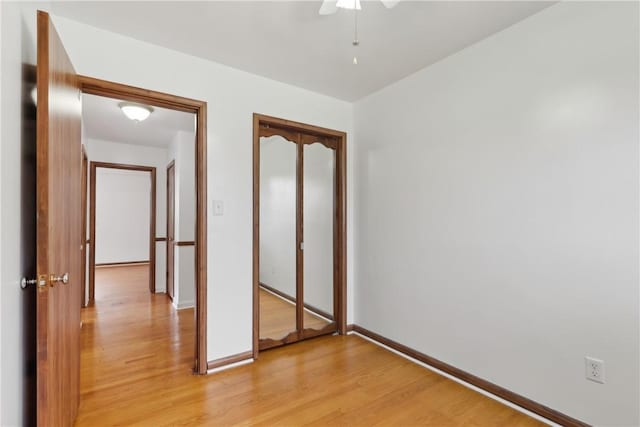 unfurnished bedroom with light wood-style floors, baseboards, a closet, and a ceiling fan