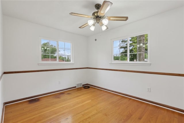 unfurnished room featuring plenty of natural light, wood finished floors, baseboards, and ceiling fan
