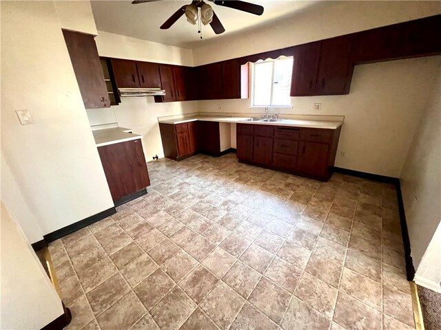 1244 Maple Ave, Monessen, PA 15062 - kitchen with under cabinet range hood, ceiling fan, baseboards, light stone finish floors, and a sink