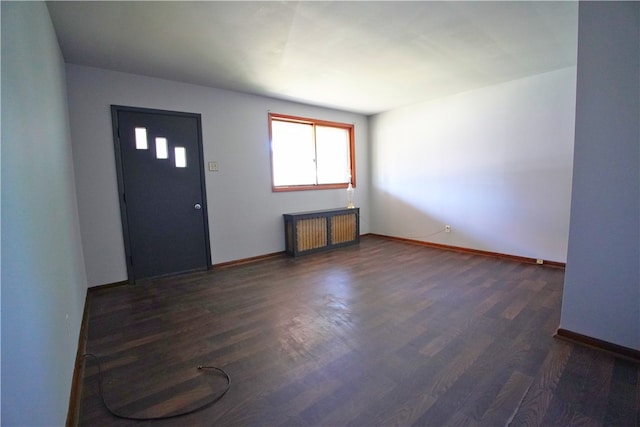 foyer entrance featuring radiator heating unit, dark wood-style floors, and baseboards