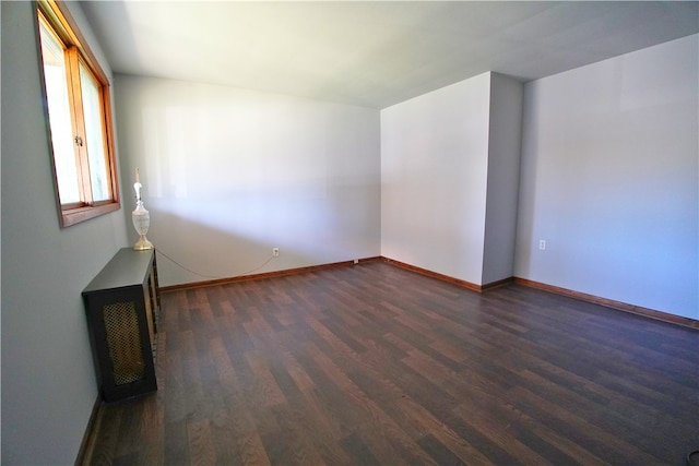 spare room featuring dark wood finished floors and baseboards