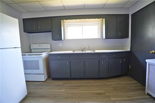 kitchen with white appliances, a sink, light wood-style floors, and light countertops