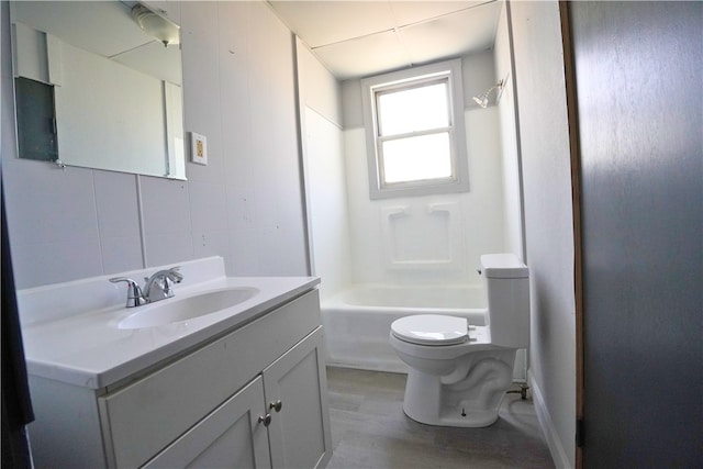 bathroom featuring wood finished floors, toilet, vanity, and washtub / shower combination