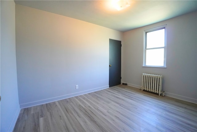 spare room featuring radiator heating unit, wood finished floors, and baseboards