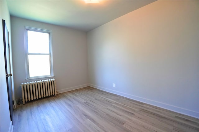 empty room with radiator, wood finished floors, and baseboards