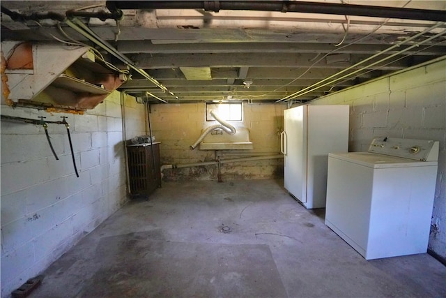 unfinished basement with washer / clothes dryer and freestanding refrigerator