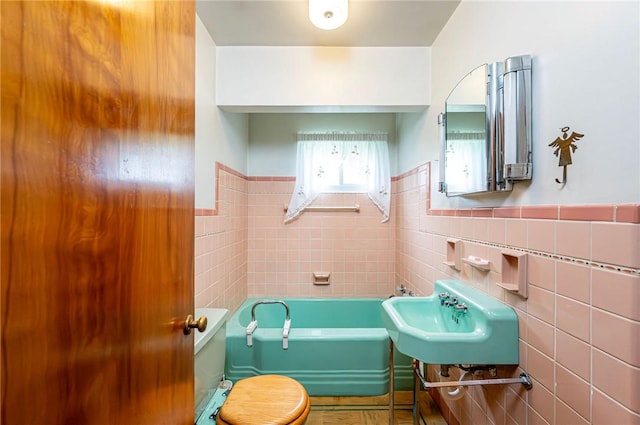 642 Washington St, Fairfield Twp, PA 15923 - bathroom with tile walls, a garden tub, wainscoting, and a sink