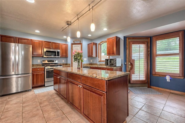 1057 Finchley Rd, North Huntingdon, PA 15642 - kitchen featuring appliances with stainless steel finishes, light tile patterned flooring, a kitchen island, light stone countertops, and a textured ceiling