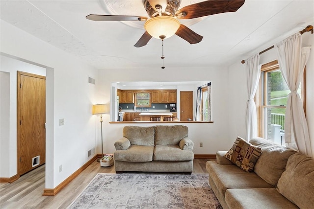 living room featuring light wood-type flooring, baseboards, and ceiling fan