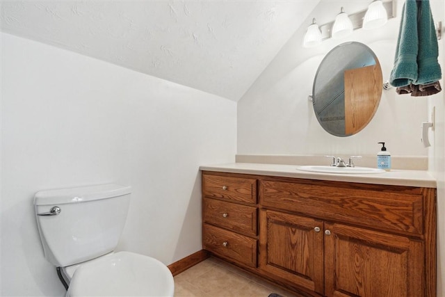 bathroom featuring lofted ceiling, toilet, tile patterned flooring, vanity, and baseboards