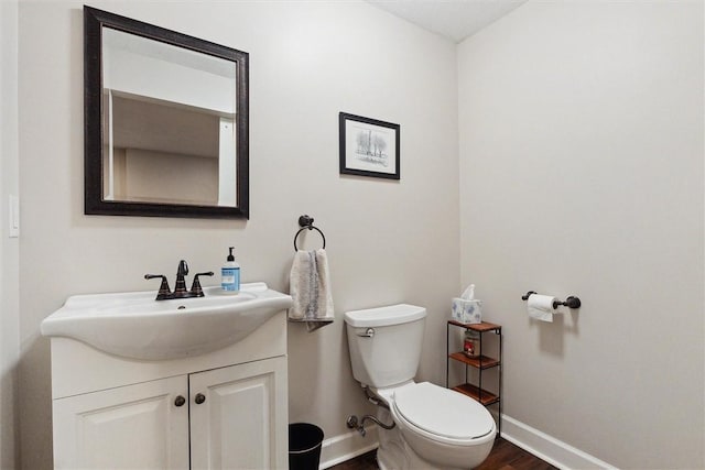 bathroom featuring baseboards, wood finished floors, vanity, and toilet