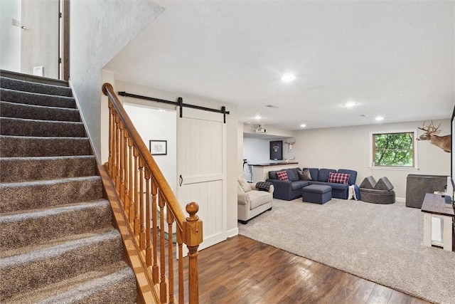 living room with a barn door, wood finished floors, stairway, recessed lighting, and baseboards