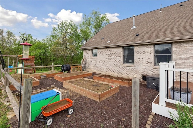 exterior space featuring roof with shingles, brick siding, and a garden