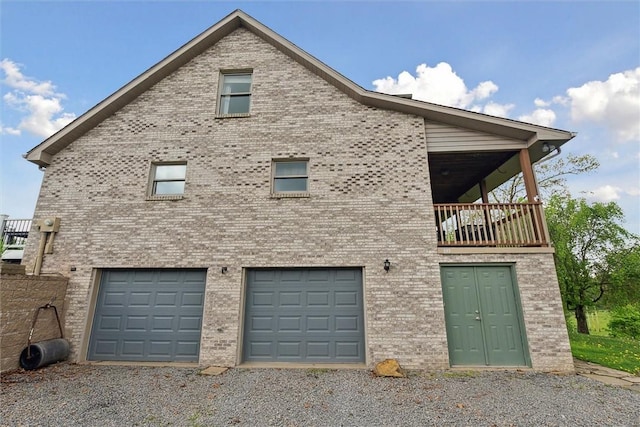 view of side of property with driveway, an attached garage, and brick siding