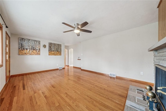 329 Sarah St, Mckees Rocks, PA 15136 - unfurnished living room with a ceiling fan, light wood finished floors, arched walkways, a stone fireplace, and baseboards